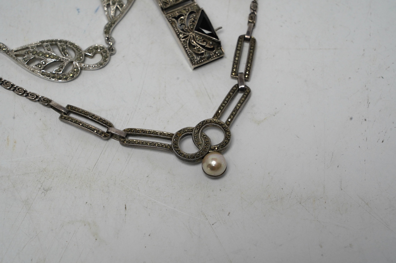 An early to mid 20th century white metal, mother of pearl and coral bead set drop pendant necklace, overall 60cm, together with two white metal and marcasite set necklaces, one stamped 925 and a German 935 marcasite and
